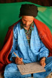 Image du Maroc Professionnelle de  Sous une tente on découvre la méthode traditionnelle de l’enseignement et l’apprentissage du saint coran prodigués aux enfants. Les jeunes récitent les sourates devant le Fkih (instituteur) qui écoute attentivement les versets ainsi récités, Samedi 18 septembre 2006, aux environ de Tan Tan dans un site désertique sur lequel la ville, a toujours accueilli la majorité des tribus et des grandes familles nomades du désert lors d'un grand Moussem, danses chants, course de chameaux et fantasia font partie des festivités. (Photo / Abdeljalil Bounhar)

